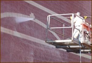 A technican flushes spent cleaner and dissolved contaminants from an architectural block wall. Using low pre-wet-and-rinse pressure (less than 1,000 psi) and high gallons per minute (6-8), is one of the secrets to a great new construction clean down