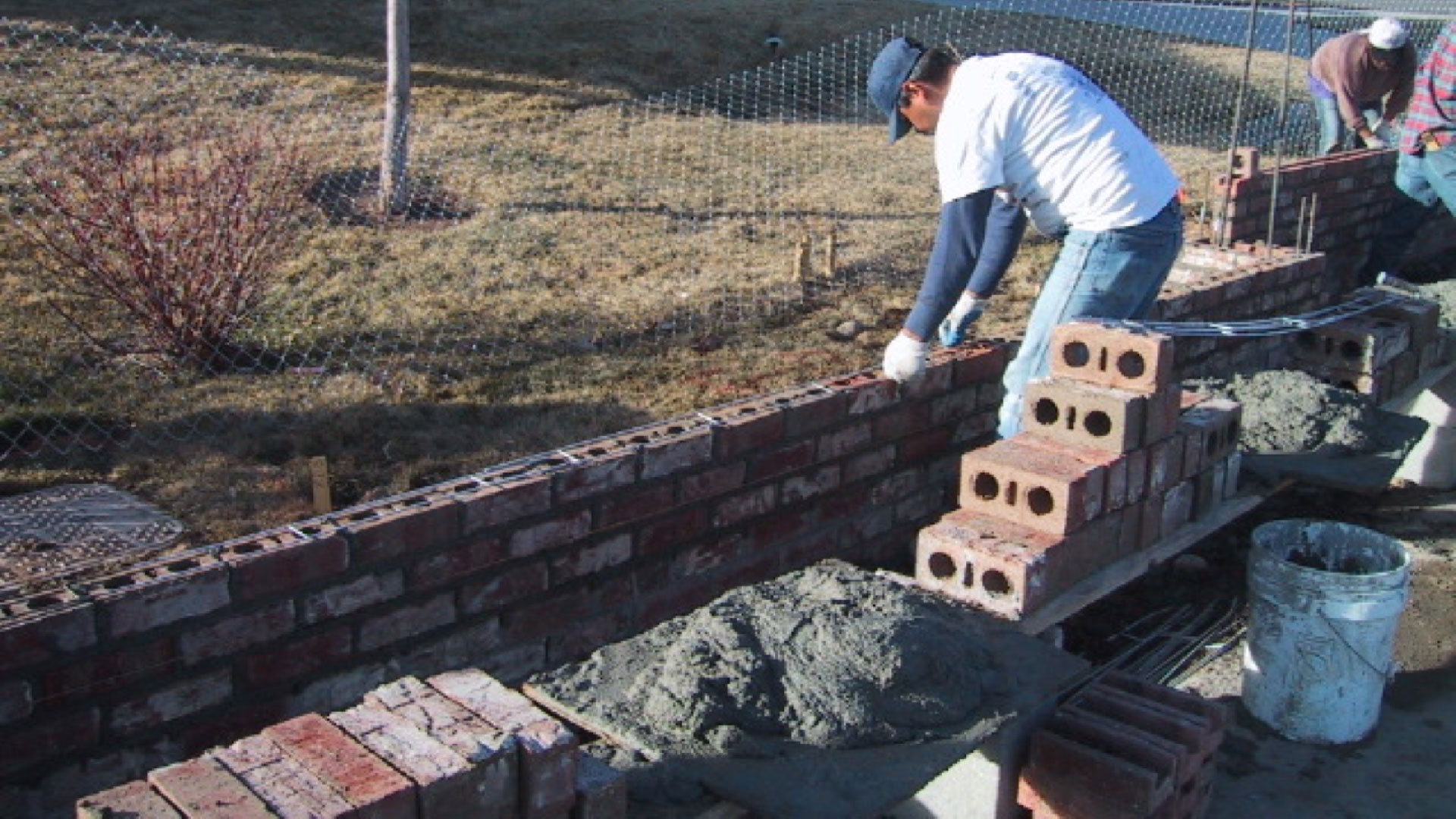 Mason placing joint reinforcement in brick “Pier and Panel” sound wall. This type of site wall does not have a continuous footing, and the joint reinforcement helps the panel act as a deep beam spanning between columns on drilled piers. Mason placing joint reinforcement in brick “Pier and Panel” sound wall. This type of site wall does not have a continuous footing, and the joint reinforcement helps the panel act as a deep beam spanning between columns on drilled piers.