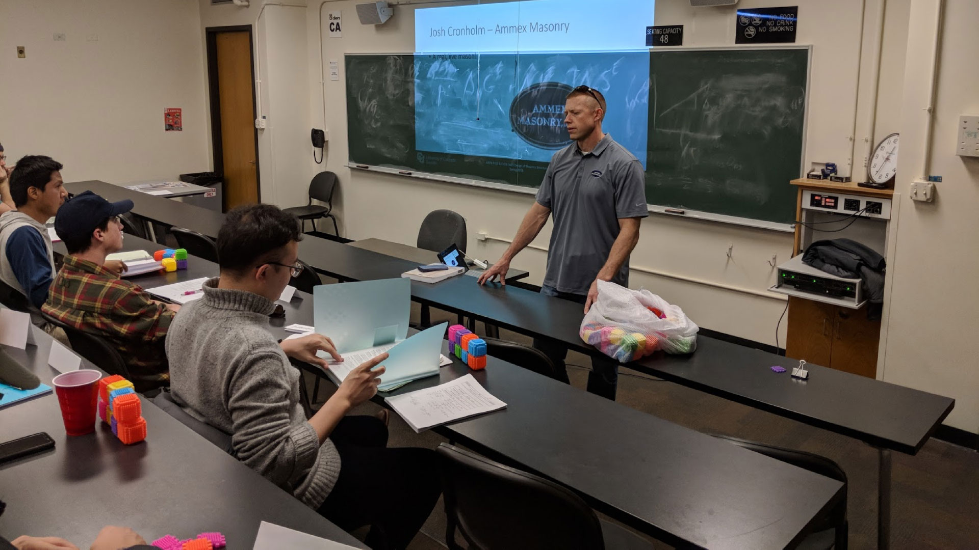 Figure 4. Josh Cronholm of Ammex Masonry (MCAA Member) speaking to university students about rebar cell crowding and demonstrating masons' tools in class. Figure 4. Josh Cronholm of Ammex Masonry (MCAA Member) speaking to university students about rebar cell crowding and demonstrating masons' tools in class.